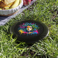 Colorful Medusa illustration on a black background, next to a picnic setup, showcasing the vibrant Neon Medusa Flying Disc.
