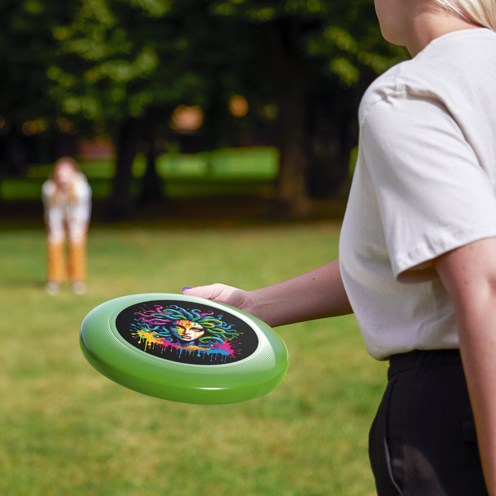 Brightly colored flying disc featuring a vibrant Medusa illustration, with people enjoying outdoor activities in the background.