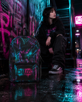 Vibrant Neon Graffiti CHAOS Backpack in teal and magenta, set against an urban backdrop with neon lights.